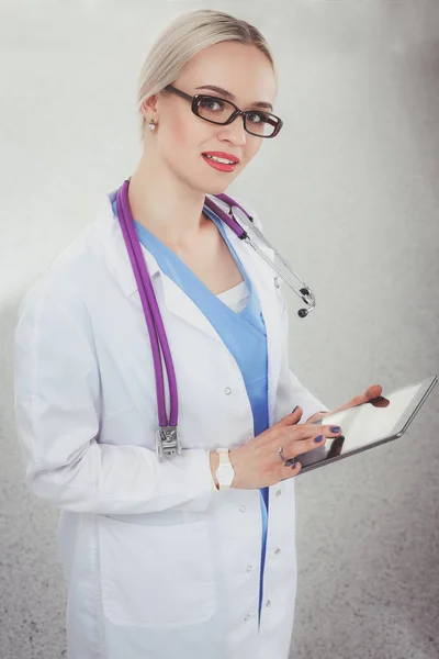 Médecin féminin utilisant une tablette numérique et debout sur fond blanc. Femmes médecins. — Photo