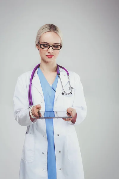 Женщина врач с помощью цифровой таблетки и стоя на белом фоне. Женщины-врачи. — стоковое фото