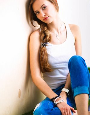 çimenlerin üzerinde kitapla oturan genç kadın