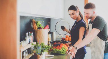 Bir çift evdeki mutfaklarında birlikte yemek pişiriyor.