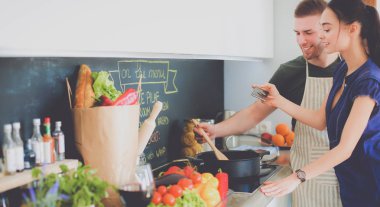 Bir çift evdeki mutfaklarında birlikte yemek pişiriyor.