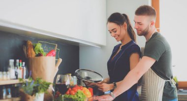 Bir çift evdeki mutfaklarında birlikte yemek pişiriyor.