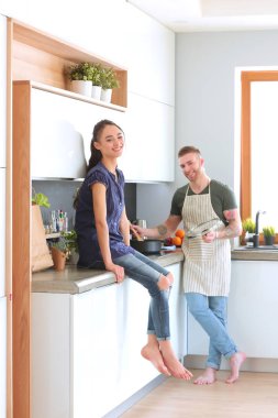 Bir çift evdeki mutfaklarında birlikte yemek pişiriyor.