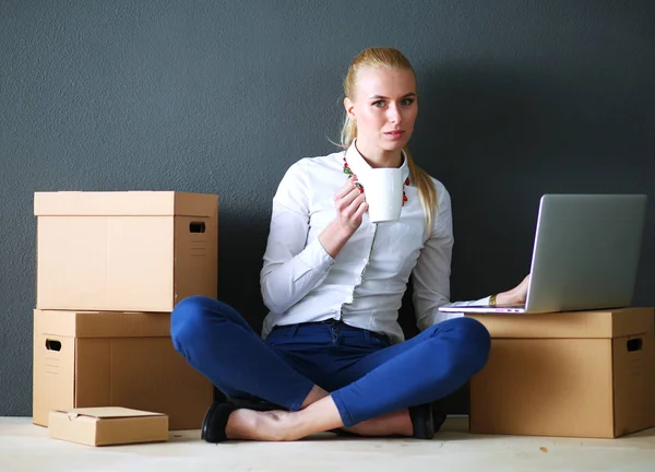 Woman sitting on the floor near a boxes with laptop . Businesswoman — Stock Photo, Image