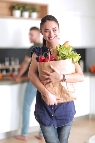 Jong stel in de keuken, vrouw met een zak boodschappen doen — Stockfoto