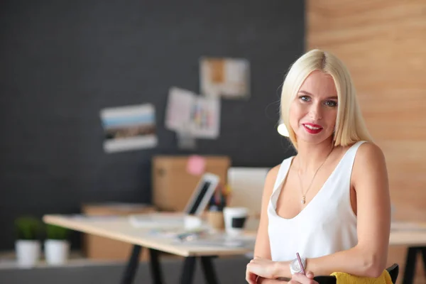Portrait of an executive professional mature businesswoman sitting on office desk