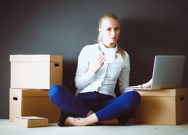 Женщина сидит на полу рядом с коробками с ноутбуком. Бизнесвумен — стоковое фото
