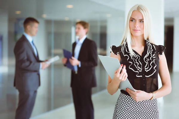 Portret van jonge zakenvrouw in functie met collega 's op de achtergrond . — Stockfoto