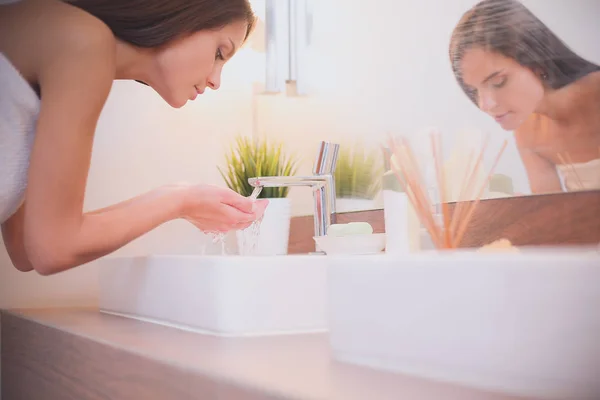 Jonge vrouw wassen haar gezicht met schoon water in badkamer — Stockfoto