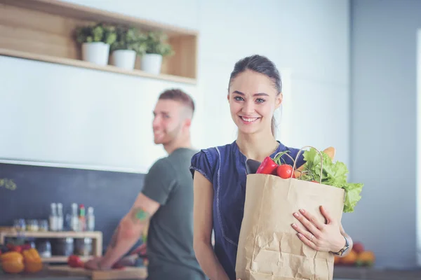 台所の若いカップル、食料品店の袋を持つ女性 — ストック写真