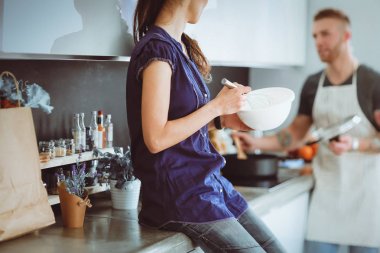 Bir çift evdeki mutfaklarında birlikte yemek pişiriyor.