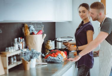 Bir çift evdeki mutfaklarında birlikte yemek pişiriyor.