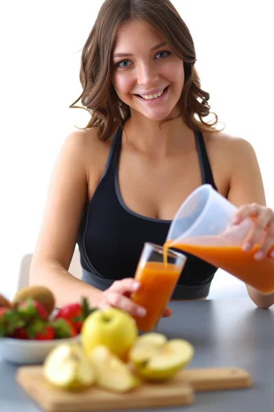 Девушка сидит на кухне на столе с фруктами и стаканами с соком — стоковое фото