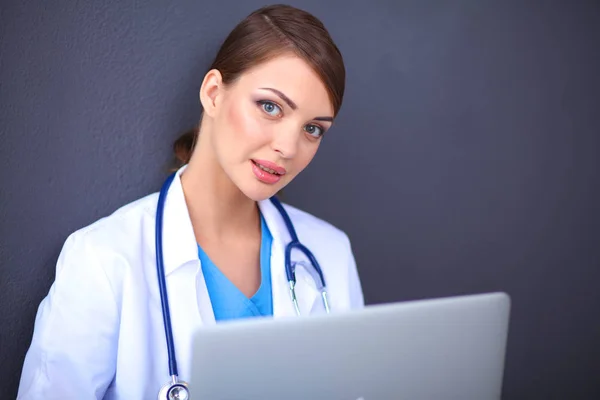 Médico femenino trabajando sentado sobre fondo gris — Foto de Stock