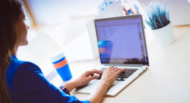 Elinde evrakları olan kadın masanın üstünde oturuyor.