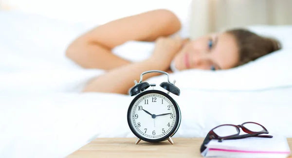 Uma jovem mulher a desligar o despertador de manhã — Fotografia de Stock