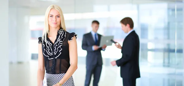 Business woman standing in foreground with a folder in her hands — Stock Photo, Image