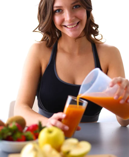 Fille assise dans la cuisine sur le bureau avec des fruits et des verres avec du jus — Photo