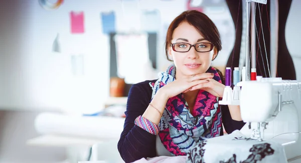 Schöne Modedesignerin sitzt am Schreibtisch im Atelier — Stockfoto