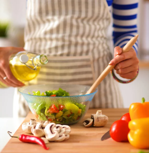 Jonge vrouw mengt verse salade — Stockfoto