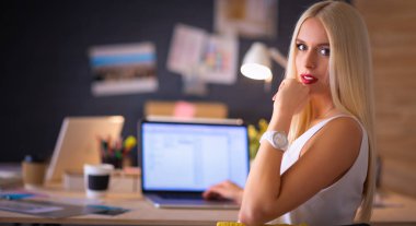 Moda tasarımcıları stüdyoda çalışıyor. Masanın üzerinde oturuyorlar.