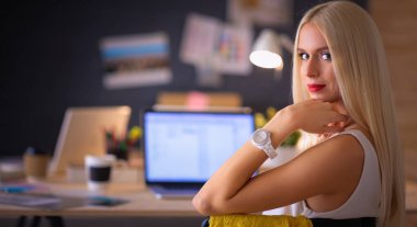 Moda tasarımcıları stüdyoda çalışıyor. Masanın üzerinde oturuyorlar.