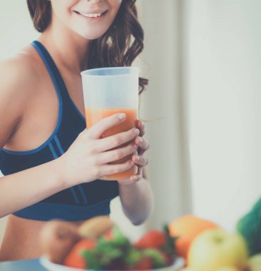 Mutfakta masada meyve suyu ve bardakla oturan bir kız.