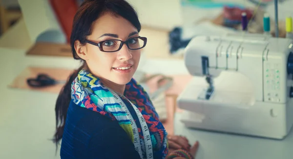 Schöne Modedesignerin sitzt am Schreibtisch im Atelier — Stockfoto