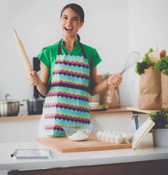 Улыбающаяся молодая женщина на кухне, изолированная на заднем плане — стоковое фото