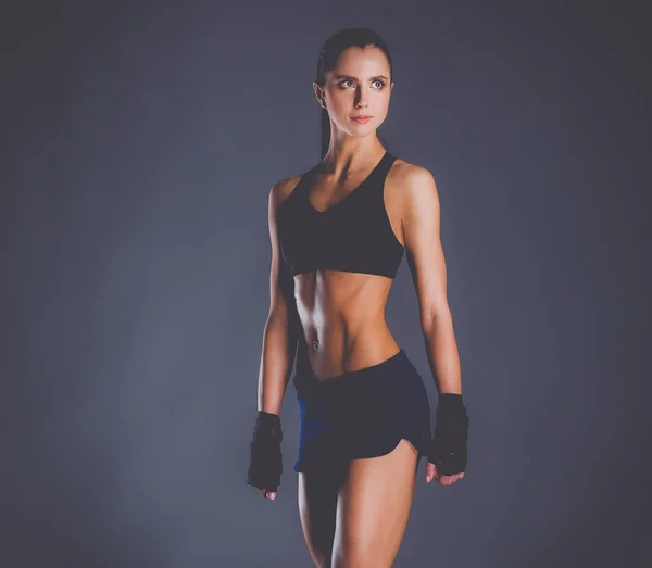 Musclé jeune femme posant en vêtements de sport sur fond noir — Photo