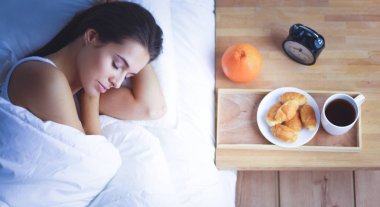 Genç ve güzel bir kadın yatakta yatıyor.