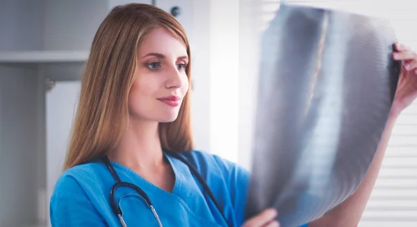 Молодая женщина-врач смотрит на рентгеновские снимки — стоковое фото
