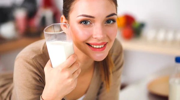 우유를 마시고, 부엌에 서 있는 젊은 여자를 웃 고 — 스톡 사진