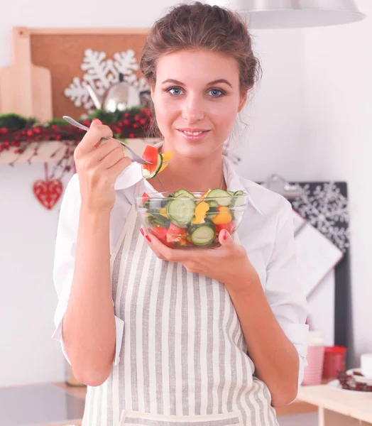 Ung kvinna äter färsk sallad i modernt kök — Stockfoto
