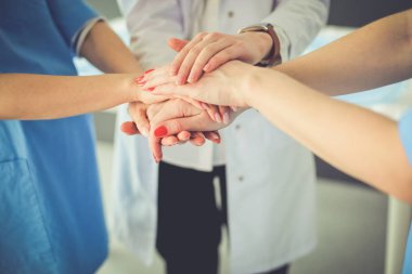 Doktorlar ve hemşireler tıbbi bir ekipte el ele tutuşuyorlar.