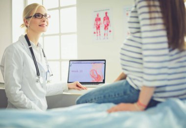 Hastanede doktorla gülümseyen güzel bir hamile kadın.