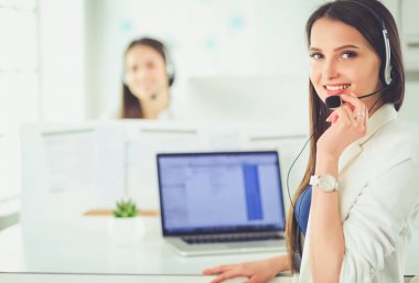 Ofisinde kulaklık ve bilgisayarla gülümseyen iş kadını ya da yardım hattı operatörü