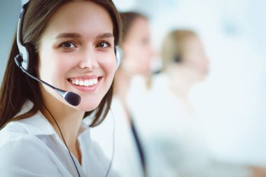 Ofisinde kulaklık ve bilgisayarla gülümseyen iş kadını ya da yardım hattı operatörü