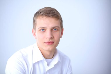 Gri arka plan üzerinde oturan gülümseyen genç adam portresi. Genç adam portresi