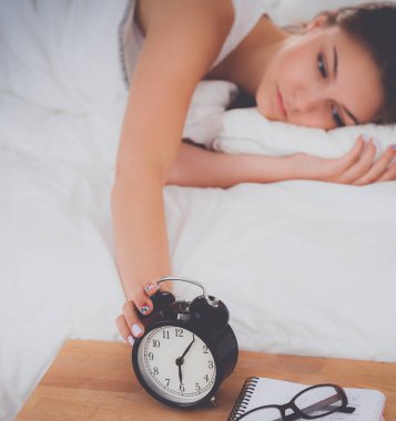 Güzel genç bir kadın, rahat ve mutlu bir şekilde yatakta uzanıyor.