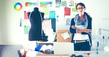 Güzel genç moda tasarımcısı stüdyoda duruyor.