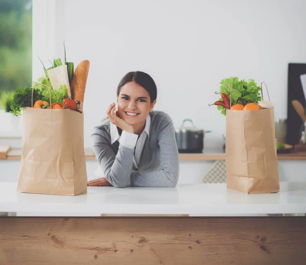 Porträtt av en leende kvinna som lagar mat i köket sittande — Stockfoto