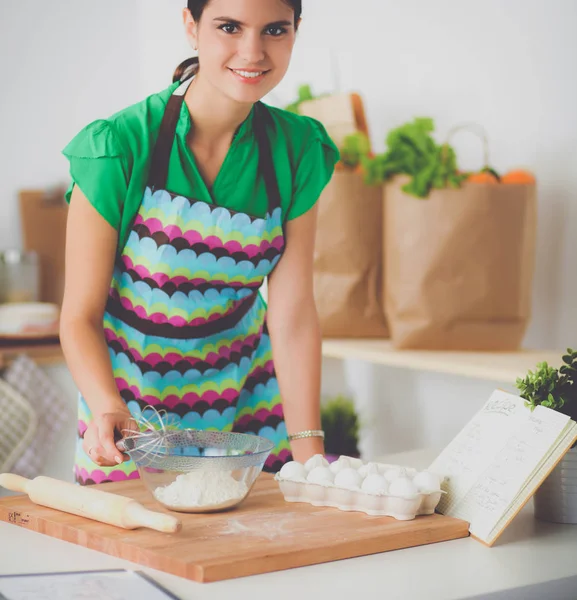 Lächelnde junge Frau in der Küche, isoliert im Hintergrund — Stockfoto