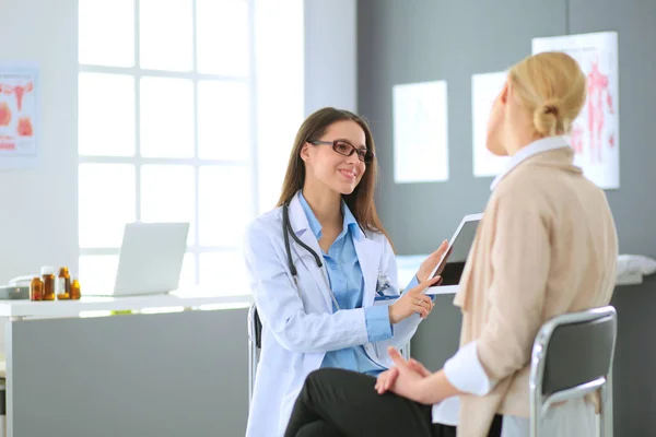 Dokter en patiënt bespreken iets terwijl ze aan tafel zitten. Geneeskunde en gezondheidszorg. Dokter en patiënt — Stockfoto