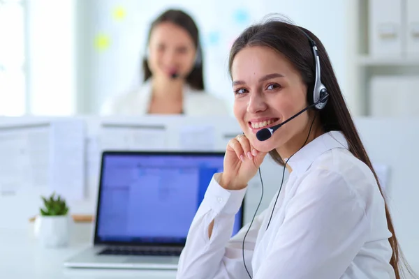 Mujer de negocios sonriente u operador de línea de ayuda con auriculares y computadora en la oficina — Foto de Stock