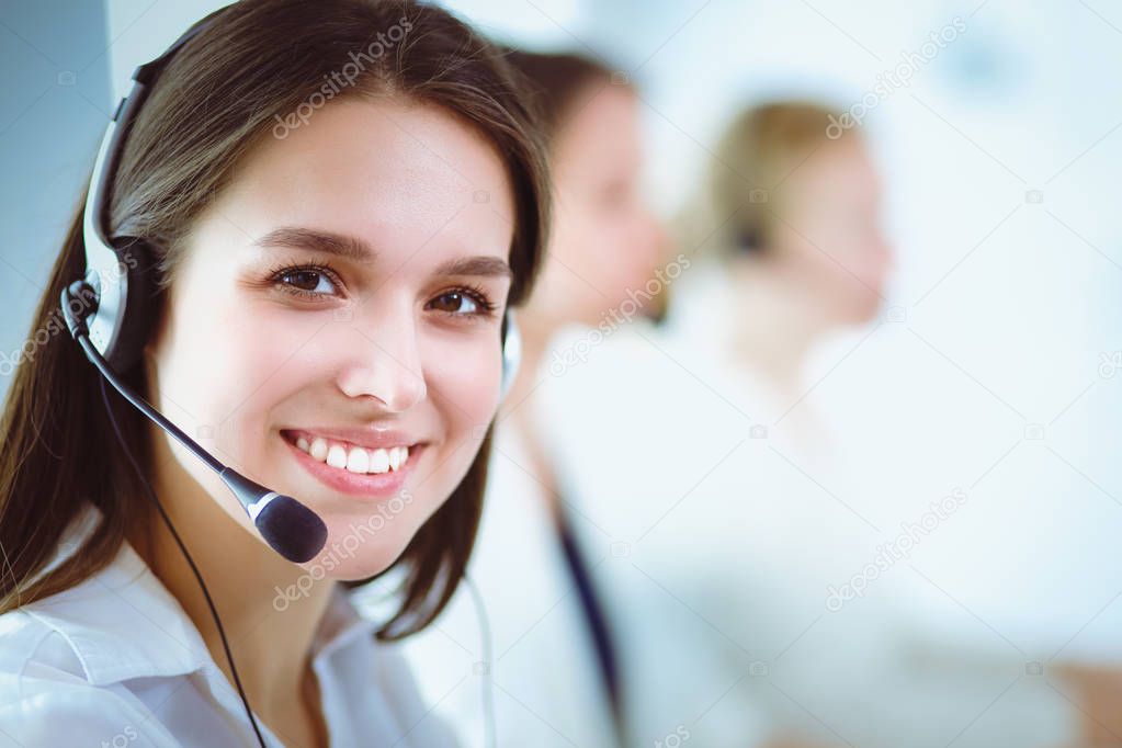 Smiling businesswoman or helpline operator with headset and computer at office