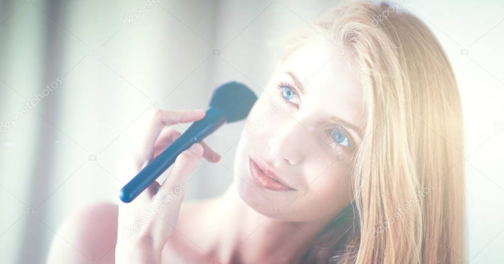 Pretty woman applying make up with brush