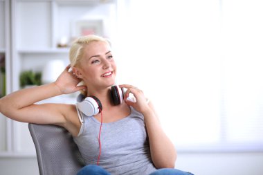 Evdeki genç ve güzel kadın kanepede oturup müzik dinliyor.