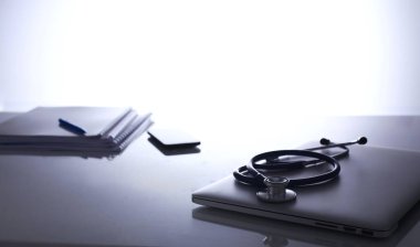 Dizüstü bilgisayarı, steteskopu ve defteri olan bir doktorun çalışma yeri.