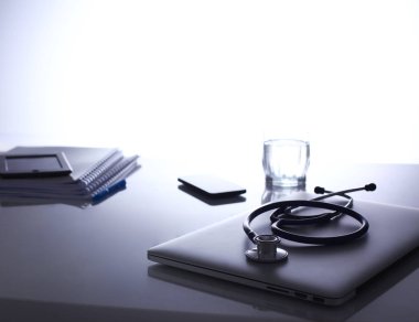 Dizüstü bilgisayarı, steteskopu ve defteri olan bir doktorun çalışma yeri.